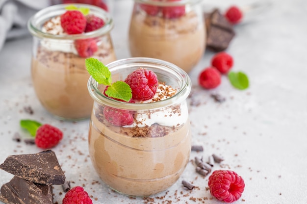 Mousse de chocolate con nata montada y frambuesas frescas en un vaso. C