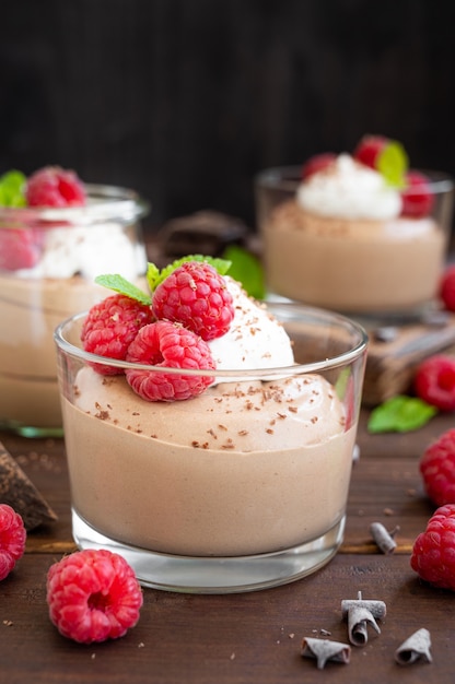 Mousse de chocolate con nata montada y frambuesas frescas en un vaso. Copie el espacio.