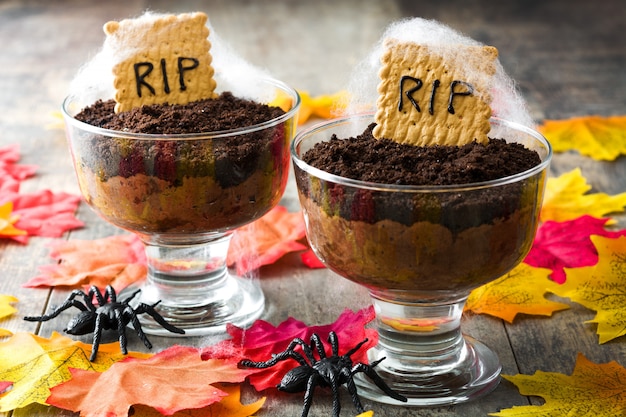 Mousse de chocolate de Halloween com cookie de tumba na mesa de madeira