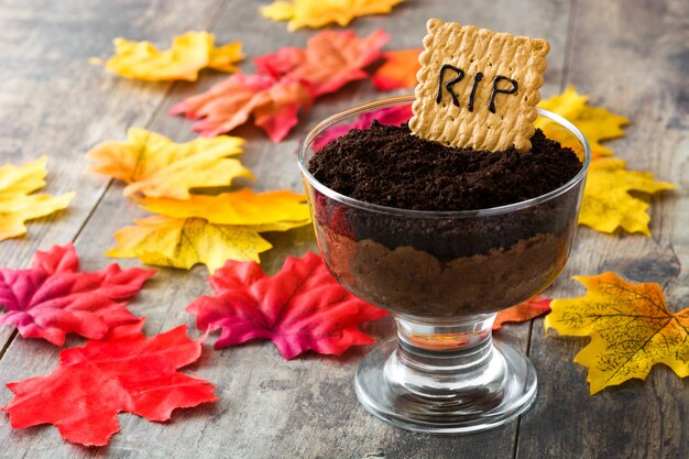 Mousse de chocolate engraçado Halloween com biscoito túmulo na mesa de madeira
