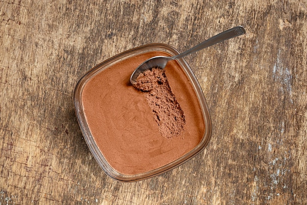 Mousse de chocolate francês tradicional em uma tigela e uma colher na velha vista superior de fundo de madeira