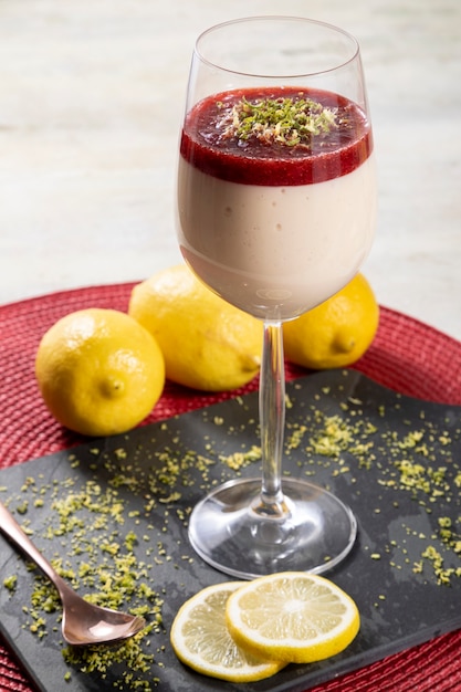 Mousse de limão em tigela de cristal com cobertura de geleia de morango e raspas de limão.