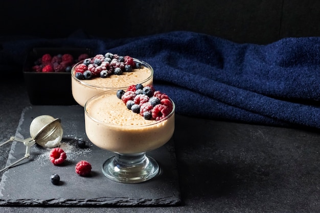 Mousse de ryazhenka (leite fermentado) em taças de vidro decoradas com frutas frescas. copie o espaço