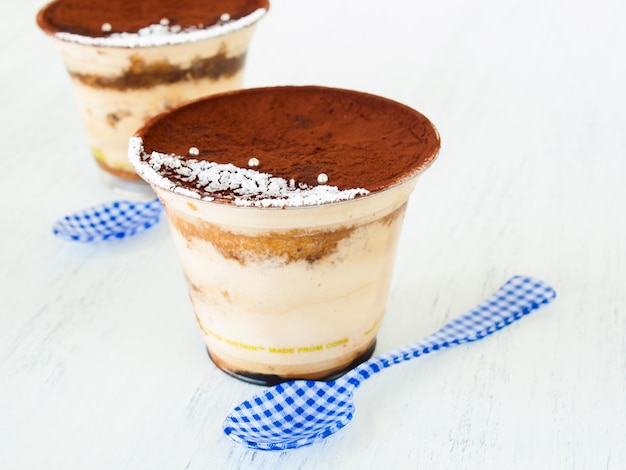 Mousse de tiramisu com decoração personalizada servida em copo plástico.