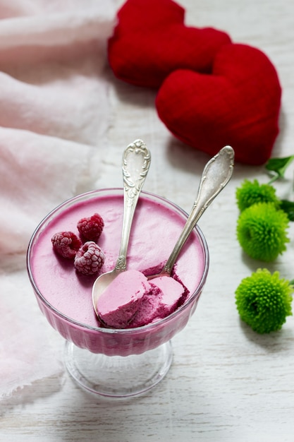 Mousse de frutas de bayas decorado con frambuesas sobre un fondo claro.