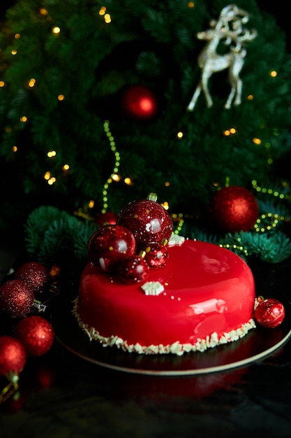 Mousse Weihnachtsgebäck Kuchen Dessert mit roter Spiegelglasur mit Neujahrsdekorationen bedeckt