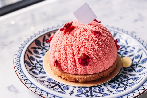 Mousses de Rosa y Lichi Decorados con pétalos de rosa en un plato de porcelana azul y blanco.