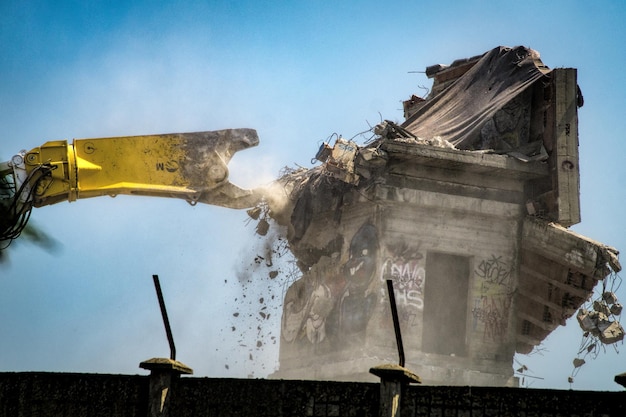 Foto movedor de terra demolindo edifício contra o céu limpo