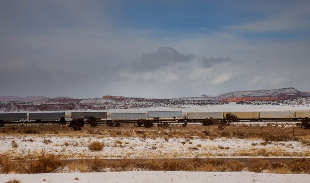 Movendo o contêiner de carga longo treina ao longo dos trilhos da ferrovia, transportando e entregando mercadorias através do deserto no arizona.