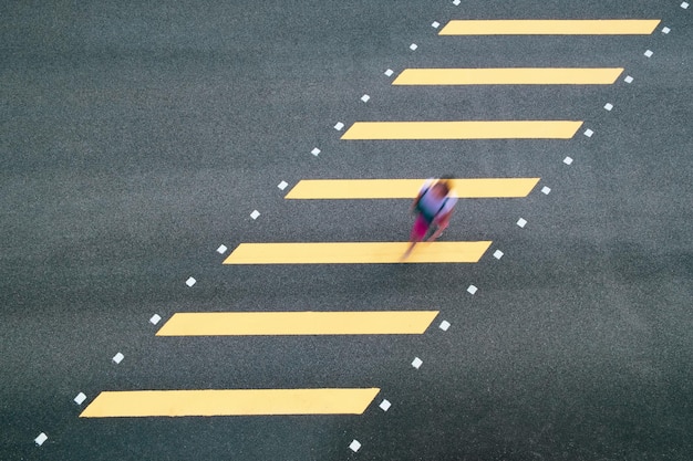 Movimento borrado de alto ângulo de mulher caminhando em uma passagem de zebra
