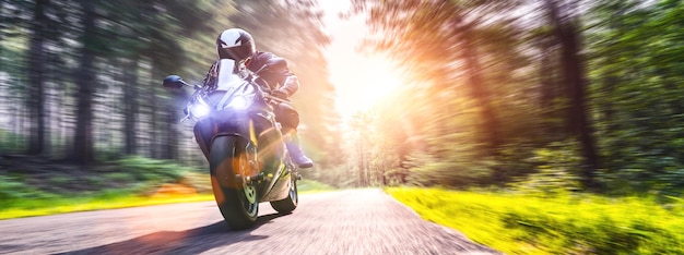 Movimento desfocado de pessoa andando de motocicleta na estrada entre árvores