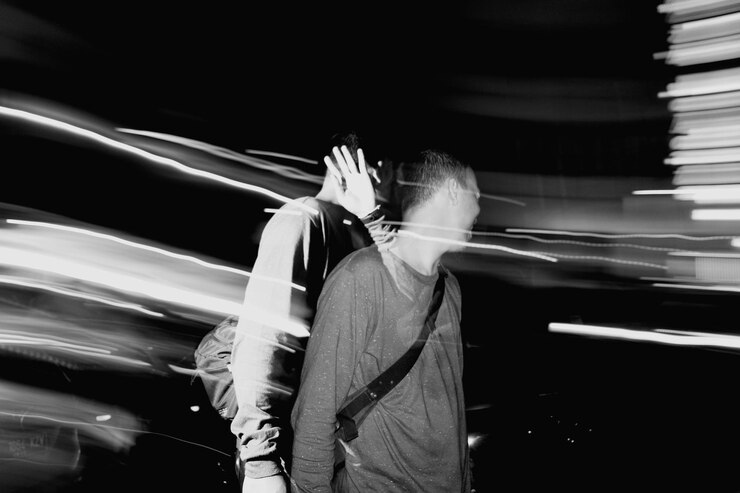 Foto movimento desfocado de um homem de pé ao ar livre à noite