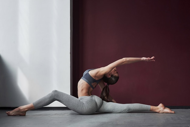 Movimentos loucos. Menina com um tipo de corpo em boa forma fazendo exercícios na sala espaçosa