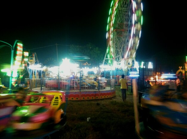 Foto movimiento borroso de atracciones iluminadas en el parque de atracciones en la feria