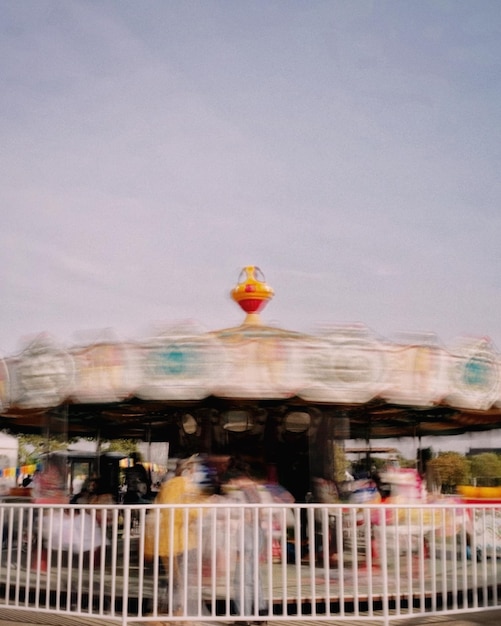 Foto movimiento borroso de la gente en el parque de atracciones contra el cielo