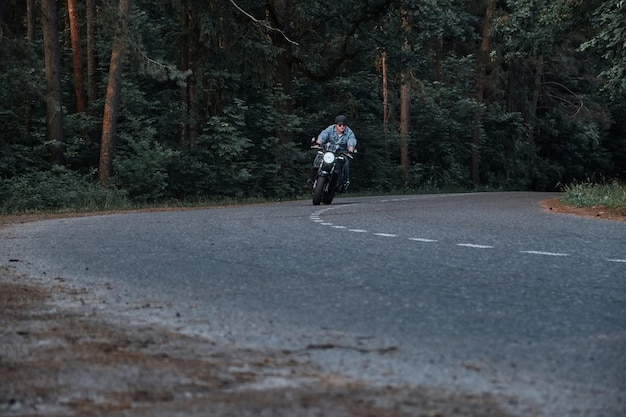 Movimiento borroso, un joven ciclista con casco viaja rápidamente a alta velocidad en un camino forestal en movimiento