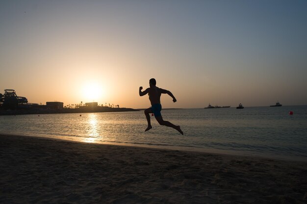 Movimiento de hombre de silueta corriendo frente al cielo del atardecer sobre la superficie del mar Nunca se detenga El éxito futuro depende de sus esfuerzos ahora Motivación diaria Estilo de vida saludable logro personal y éxito