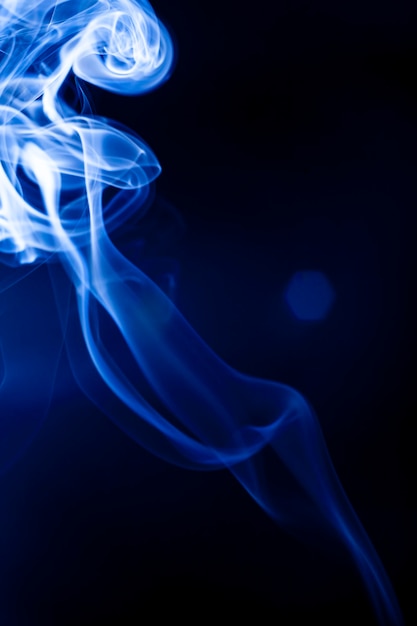 Foto movimiento humo azul sobre fondo negro.