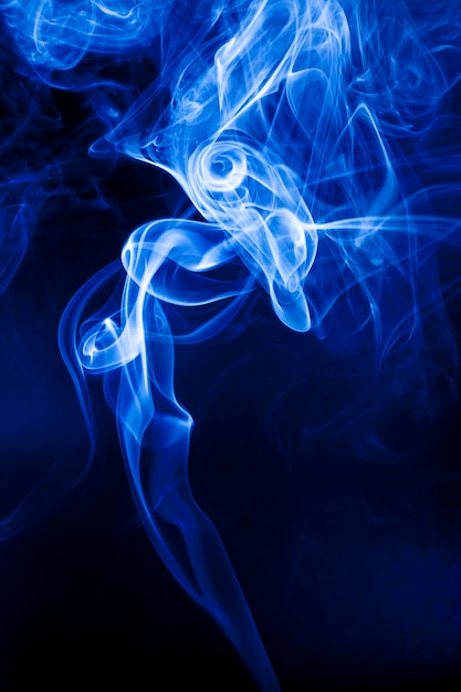 Foto movimiento humo azul sobre fondo negro.