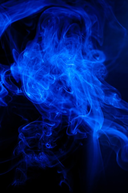 Foto movimiento de humo azul sobre superficie negra.