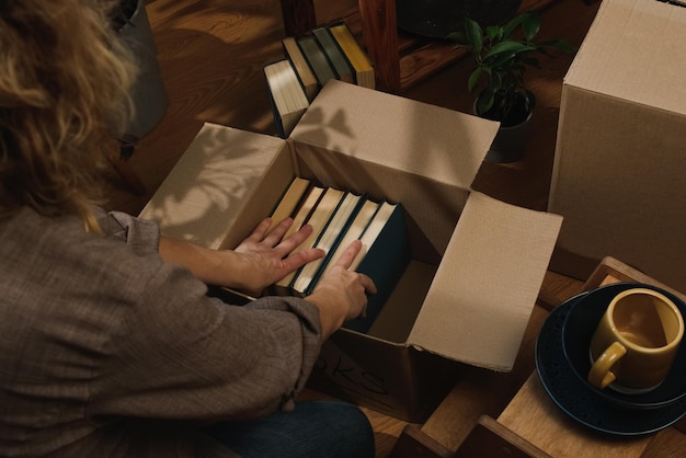 Movimiento de reubicación mujer joven empacando libros en caja de mudanzas