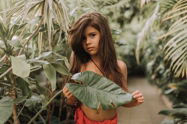 Mowgli indisches kleines Mädchen in einem Lendenschurz versteckt sich im grünen Waldhintergrund der Tropen
