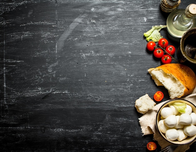 Foto mozzarella com pão fresco, tomate e verduras.