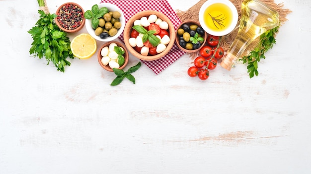 Mozzarella-Käse Kirschtomaten Basilikumblätter Öl Oliven Pfeffer Salat Caprese Auf einem weißen Holztisch Freier Platz für Text