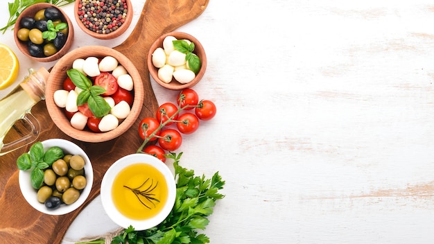 Mozzarella-Käse Kirschtomaten Basilikumblätter Öl Oliven Pfeffer Salat Caprese Auf einem weißen Holztisch Freier Platz für Text