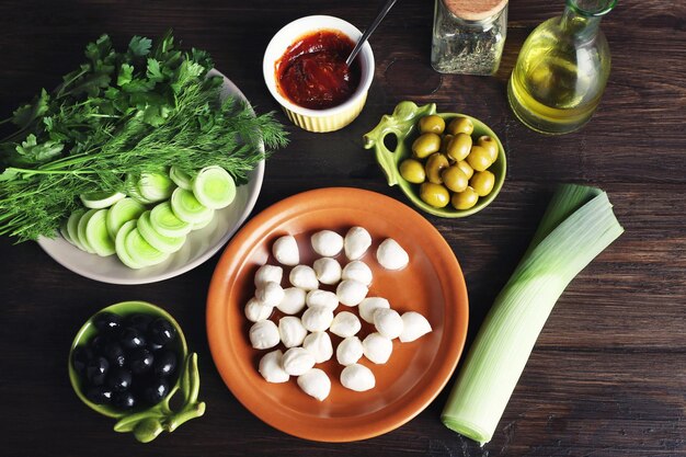 Mozzarella-Käse mit Oliven und Gemüse auf Holzhintergrund