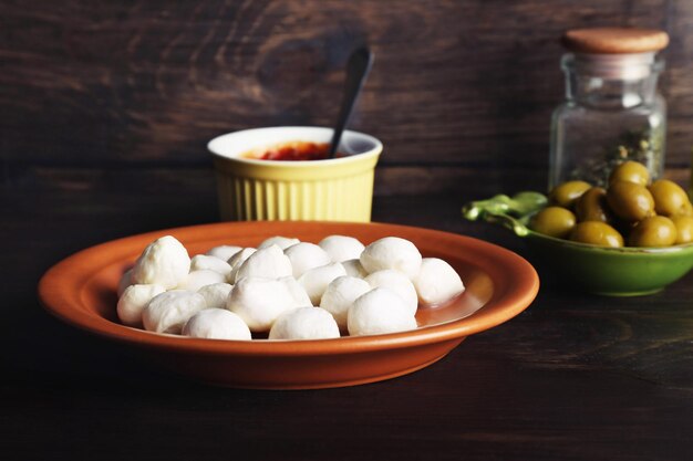 Mozzarella-Käse mit Oliven und Soße auf Holzhintergrund