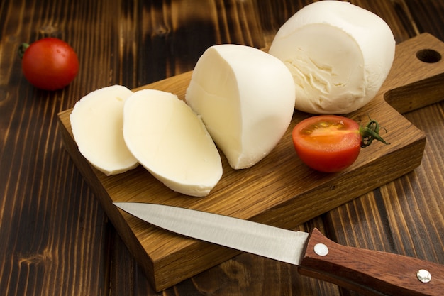 Mozzarella en rodajas sobre la tabla de cortar de madera marrón