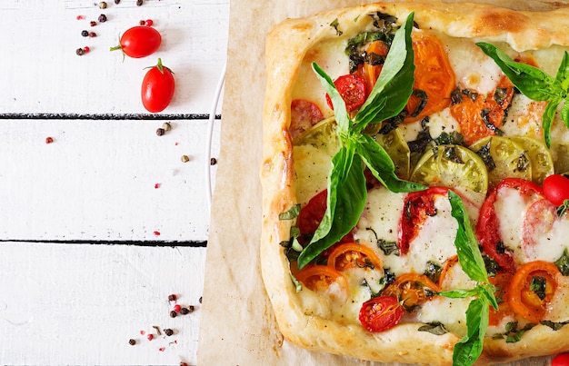 Mozzarella, tomate, pastel de albahaca sobre una mesa de madera blanca. Deliciosa comida, aperitivo en un estilo mediterráneo. Vista superior. Lay Flat