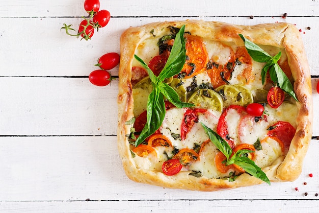 Mozzarella, tomate, pastel de albahaca sobre una mesa de madera blanca. Deliciosa comida, aperitivo en un estilo mediterráneo. Vista superior. Lay Flat