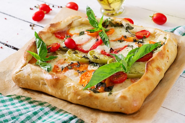 Mozzarella, tomate, pastel de albahaca sobre una mesa de madera blanca. Deliciosa comida, aperitivo en un estilo mediterráneo.