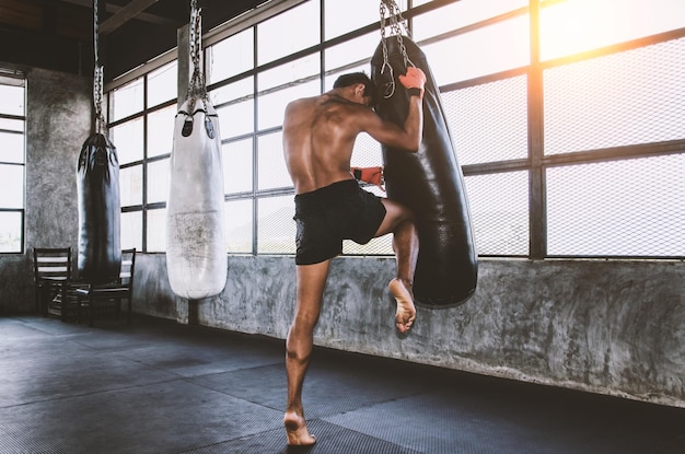 Foto muay thai fighter training im fitnessstudio mit dem boxsack