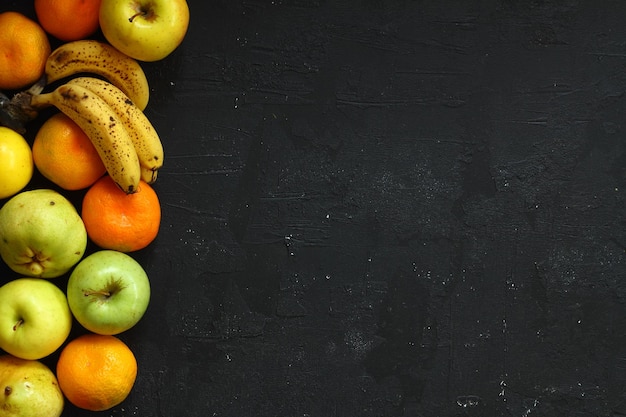 Foto mucha fruta madura y jugosa sobre un fondo negro manzanas peras plátano y mandarín juntos