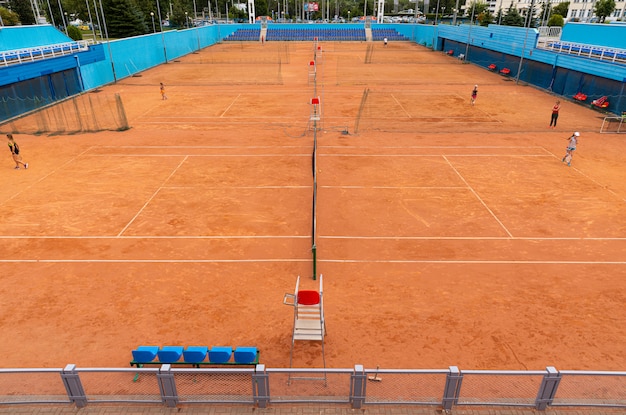 Mucha gente, niños jugando tenis en la cancha de tenis roja ronca