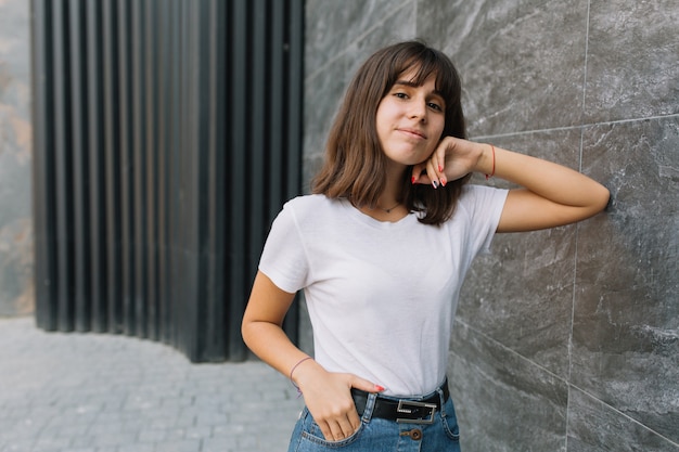 Muchacha adolescente en vidrios y apoyos que presentan cerca de la pared gris.