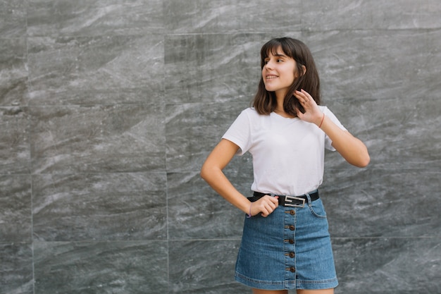 Muchacha adolescente en vidrios y apoyos que presentan cerca de la pared gris.