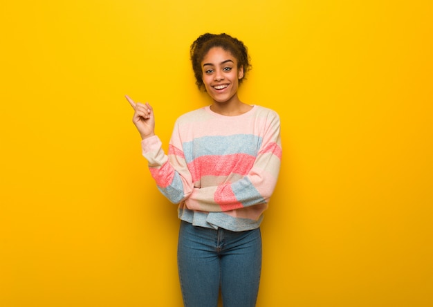 Muchacha afroamericana negra joven con los ojos azules que señala al lado con el dedo