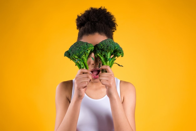 Muchacha afroamericana que sostiene el bróculi aislado.