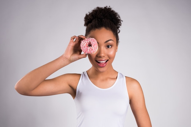 Foto muchacha afroamericana que sostiene el buñuelo aislado.