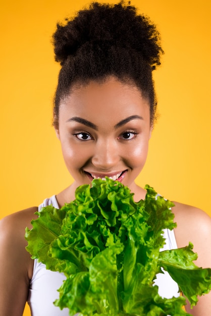 Muchacha afroamericana que sostiene la ensalada aislada.