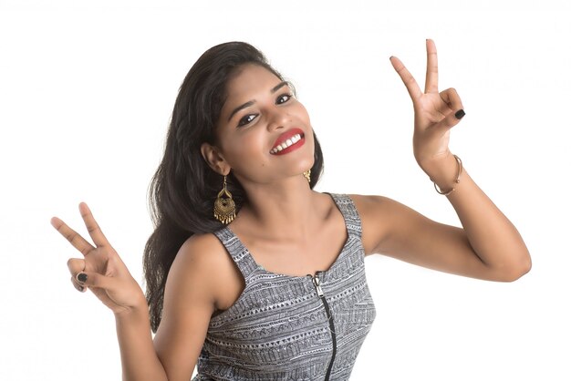 Muchacha alegre sonriente que muestra la muestra aislada en la pared blanca