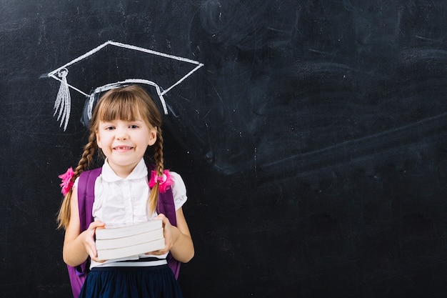 Muchacha del alumno con los libros en sombrero principal