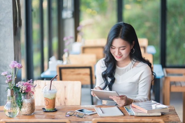 Muchacha de Asia que usa la tableta en el café