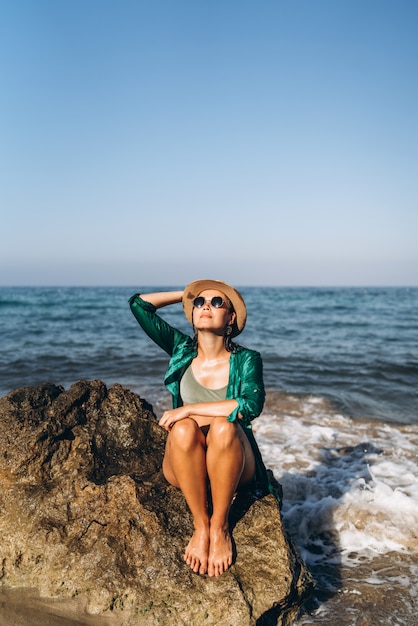 Muchacha asiática de la cacerola linda que se relaja en la playa cerca del mar en pareo verde.