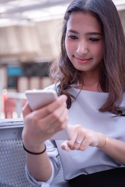 Muchacha asiática feliz del adolescente que habla el teléfono móvil con la cara sonriente