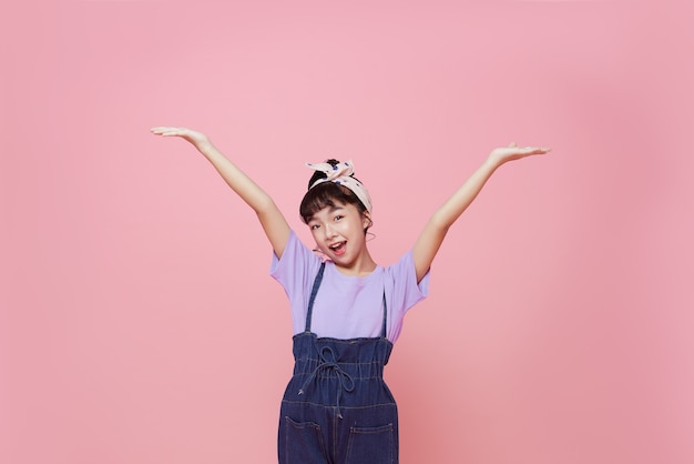 Muchacha asiática feliz del niño aislada en fondo rosado.